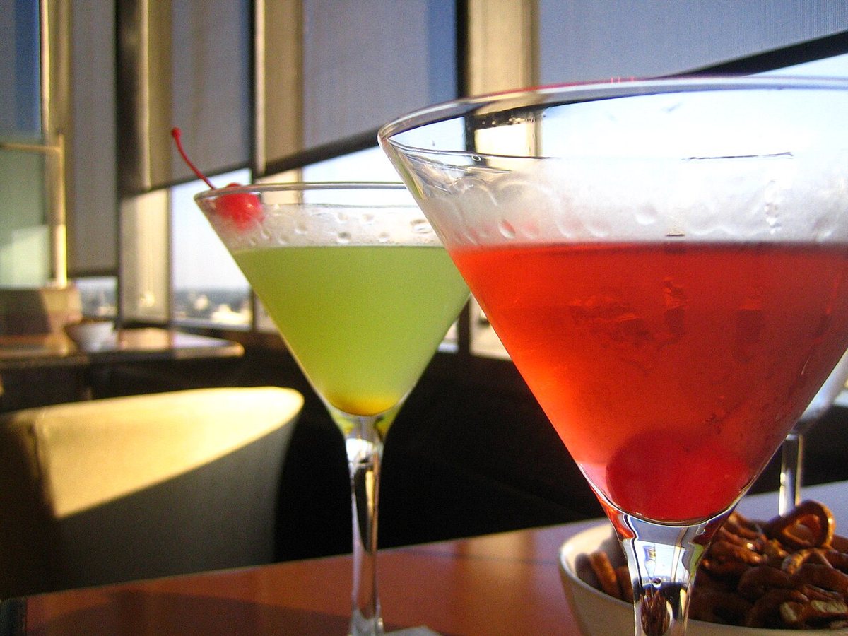 Two colorful cocktails in martini glasses on a bar