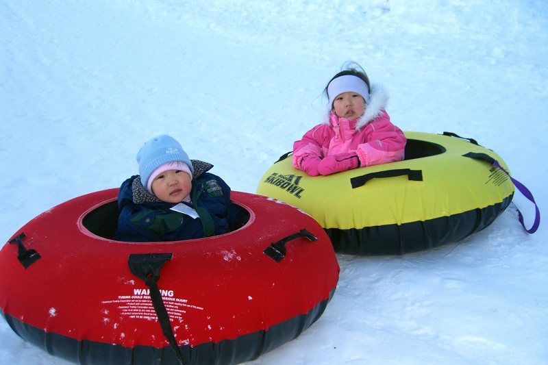 Two children in snow tubes on a snowy hill (illustrative photo, not Massanutten)