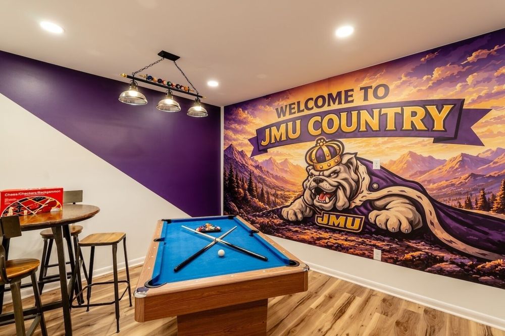 Pool table, bar seating and purple accent wall beside the JMU Country mural at Cedar Escape
