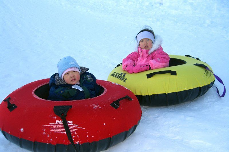 Two children in colorful snow tubes on a snowy slope (illustrative photo)