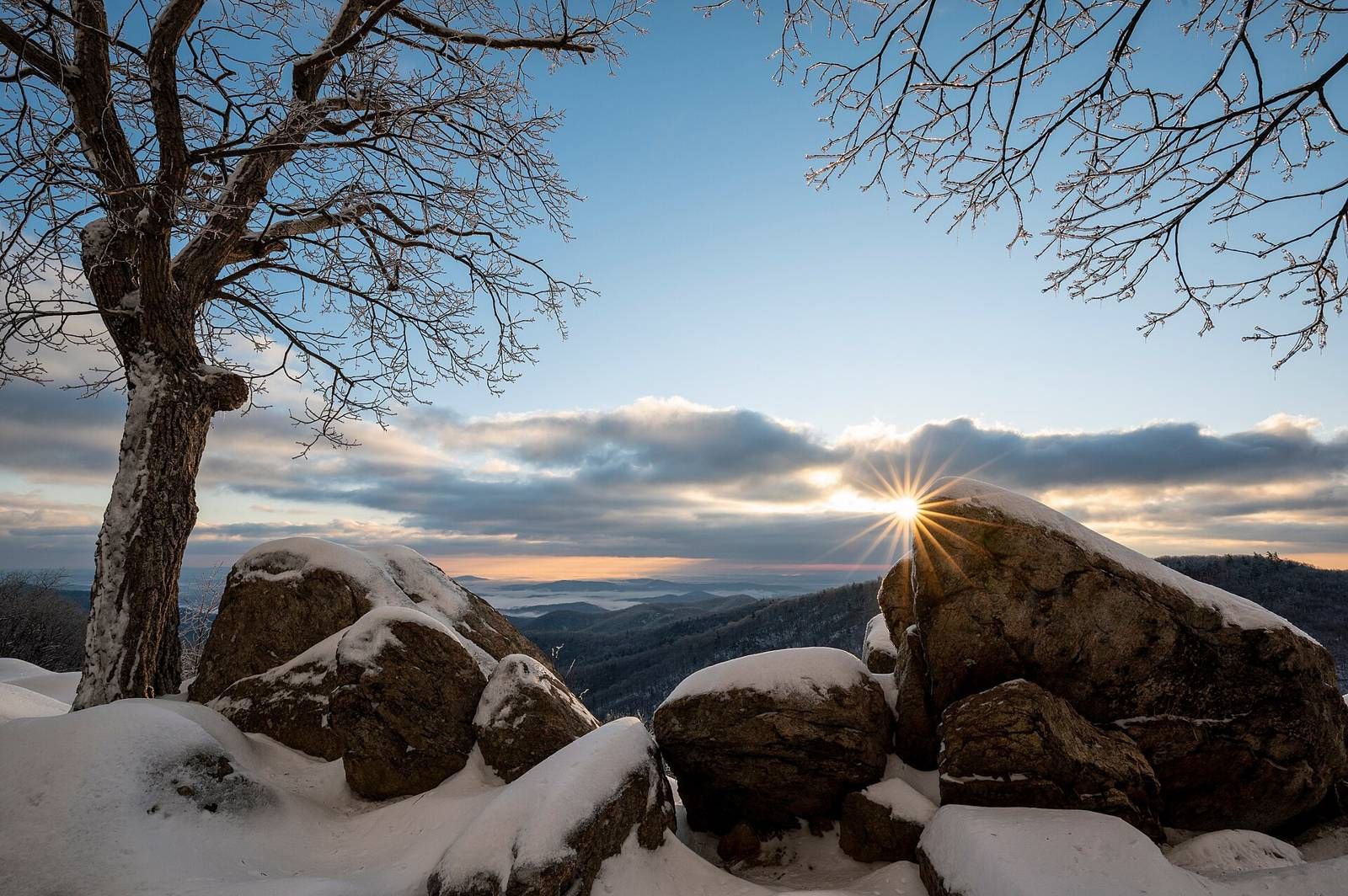 Winter sunrise over snow-covered rocks and bare trees in Shenandoah National Park